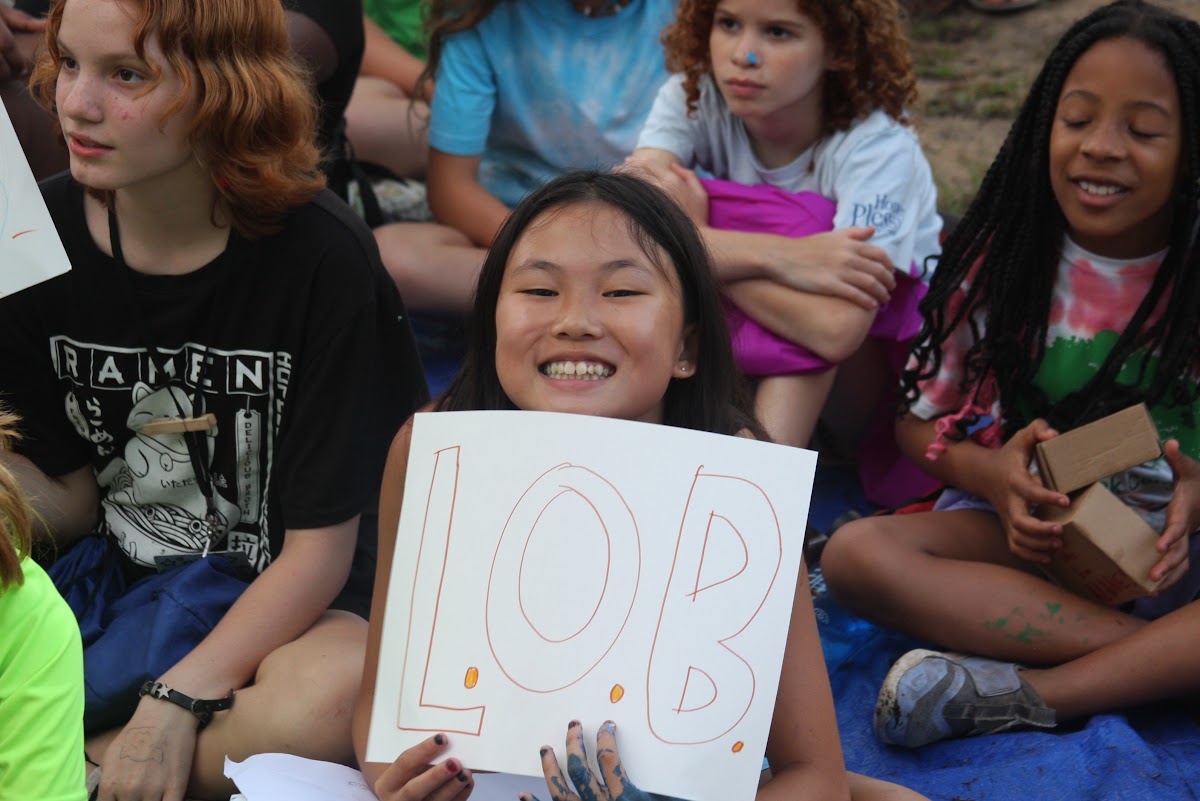 Camper holding LOB sign and smiling