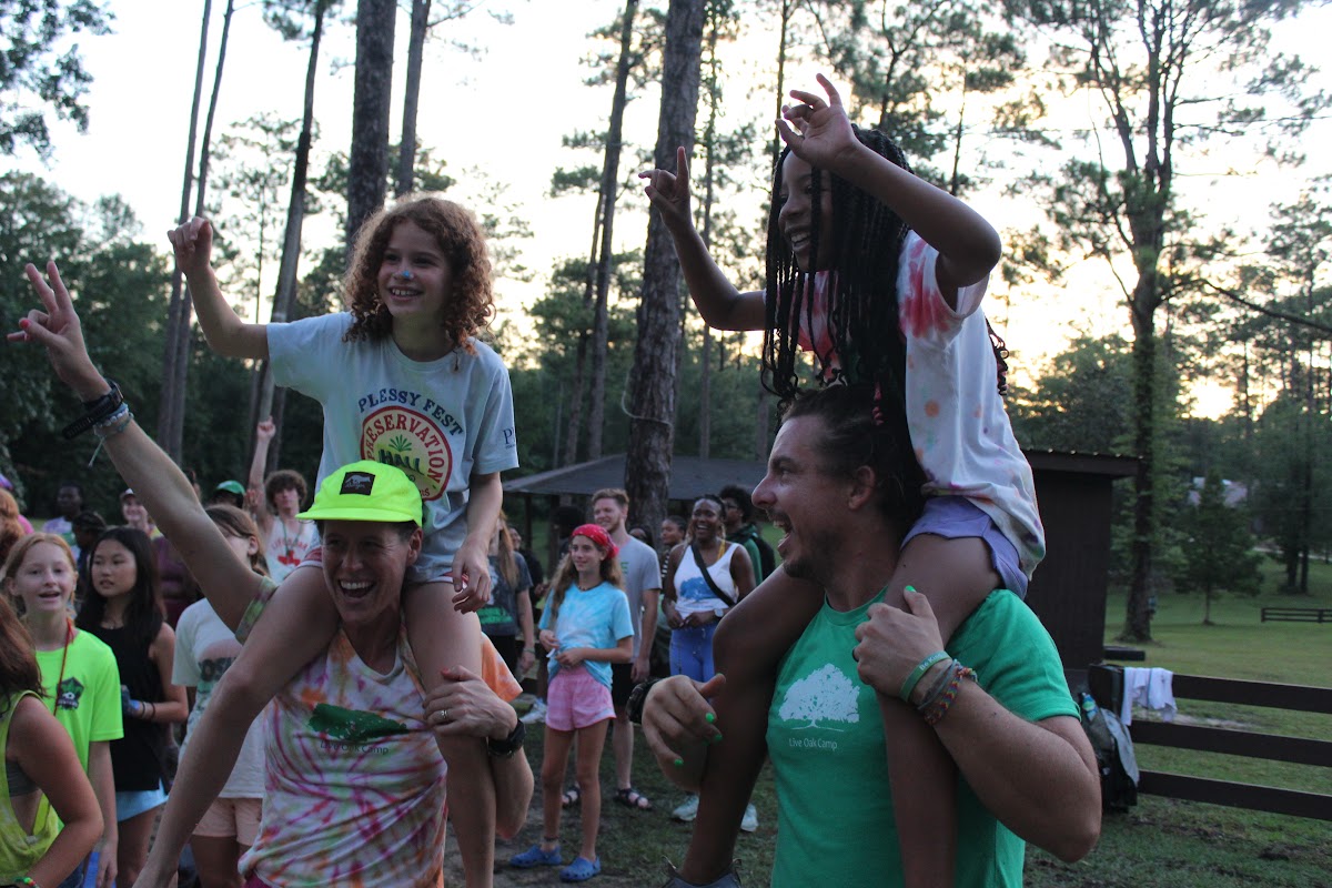 Coaches with campers on shoulders at sunset